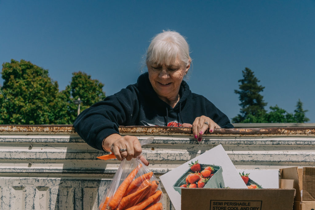 Elderly Woman Distributing Carrots